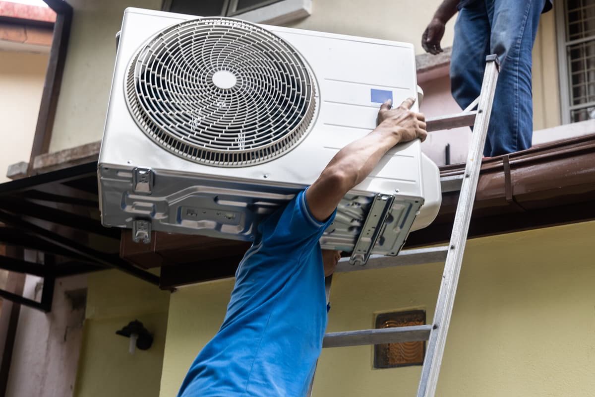 Reliance installer mounting a mini-split outdoor unit on a Southwest Florida home