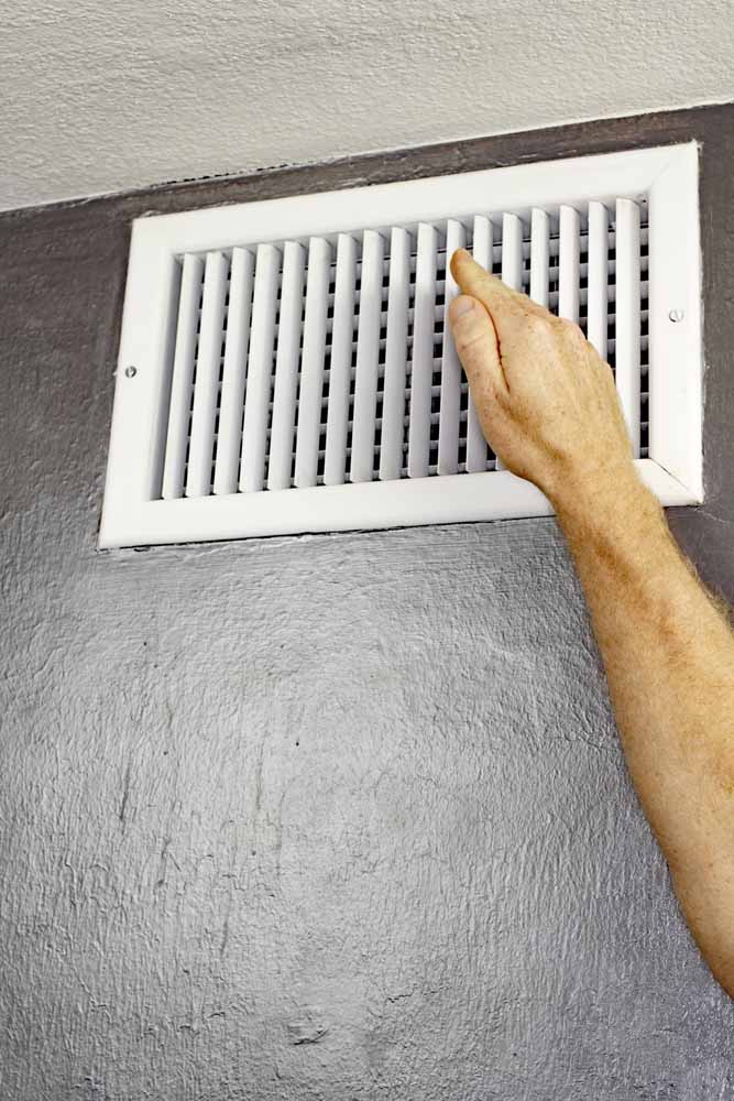 Hand hovering above HVAC vent to check airflow